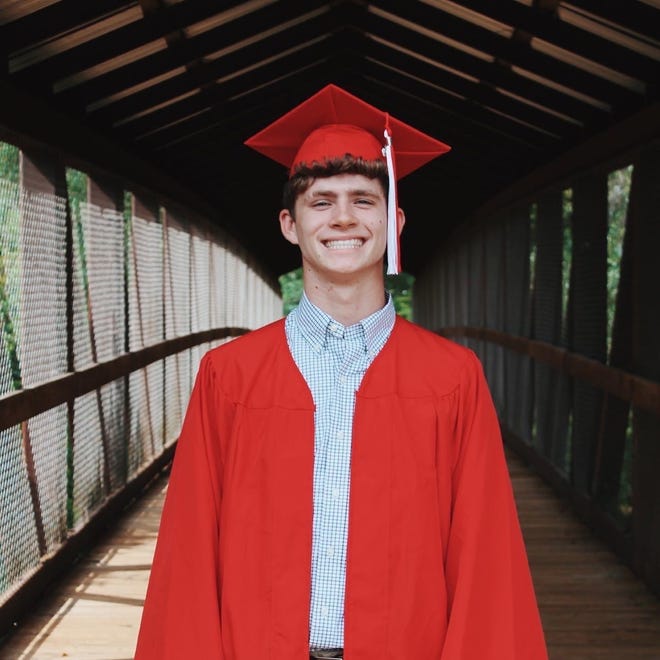 Giovanni Vitrano graduation photo in a red cap and gown on a covered bridge